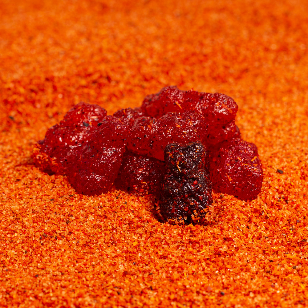 Gummy bears dulces enchliados covered in chile and chamoy mixture on top of chile powder mixture