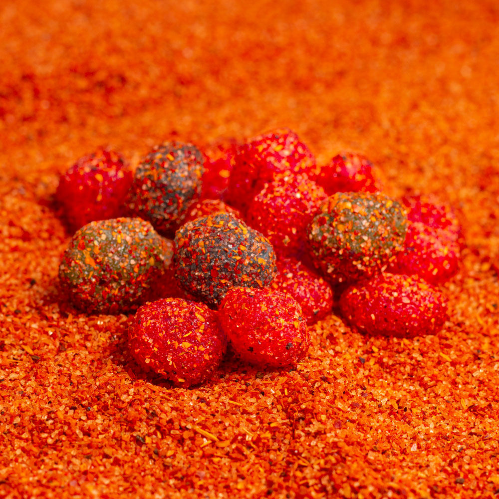 Close up of gushers covered in chile and chamoy mixture on top of chile powder