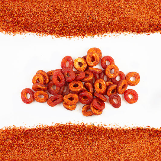 Peach rings dulces enchilados covered in chamoy and chile mixture in front of white background with a chile powder border